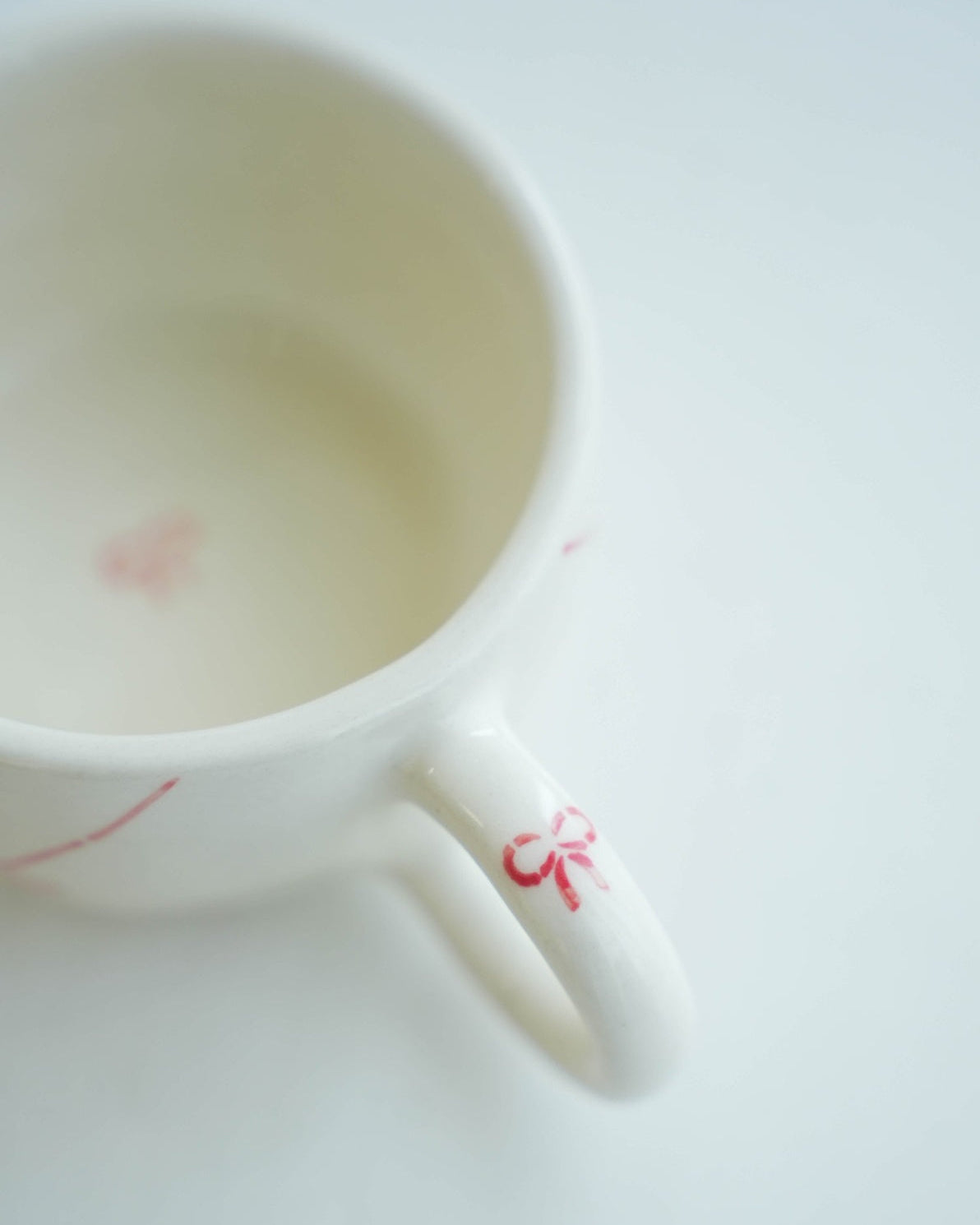 White ceramic cup with red floral design on a white background