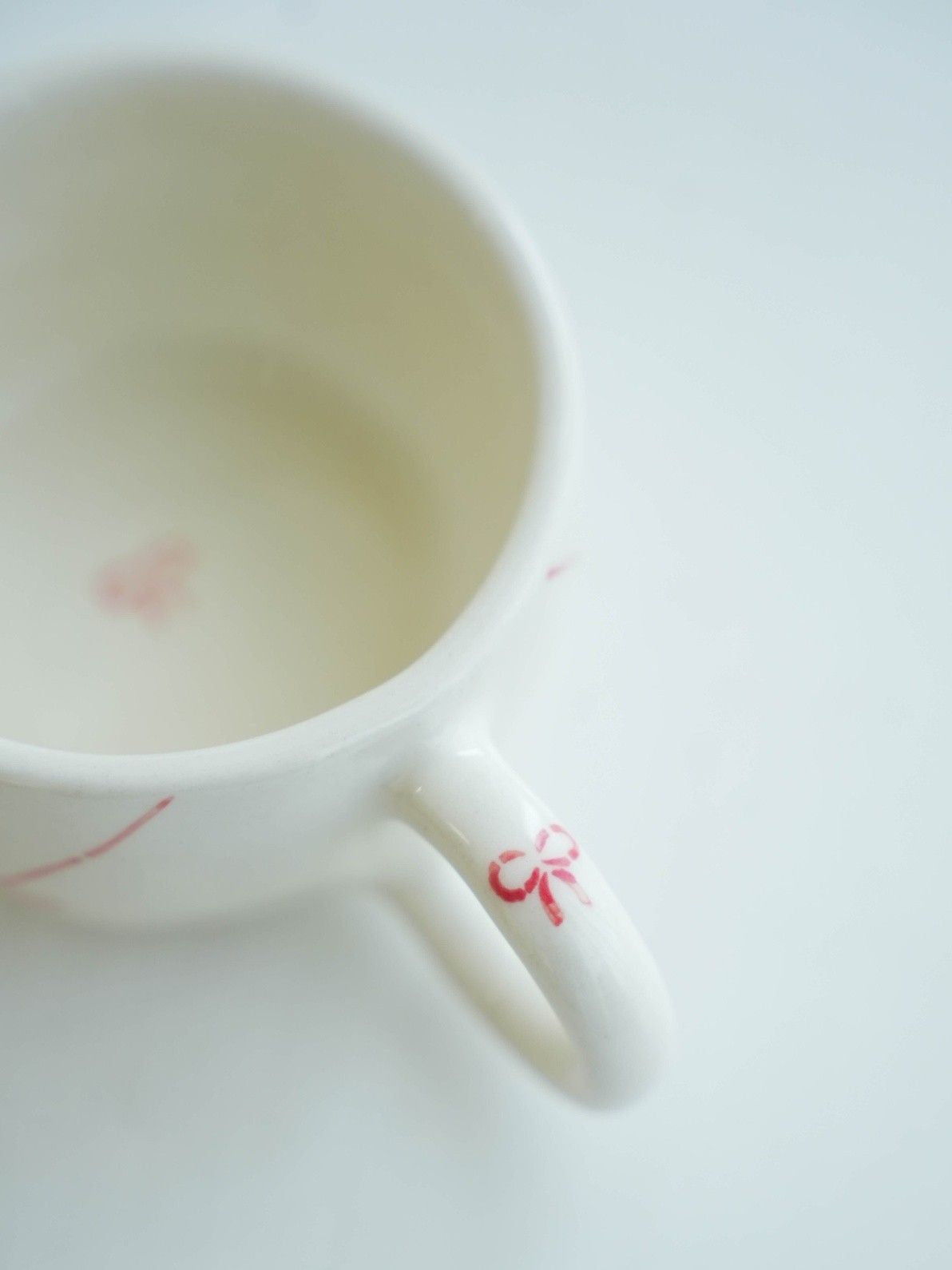 White ceramic cup with red floral design on a white background