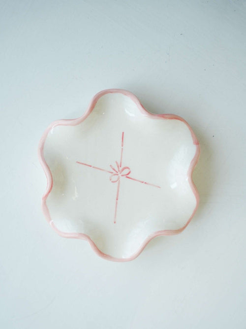 White ceramic dish with pink rim and red design on a white background