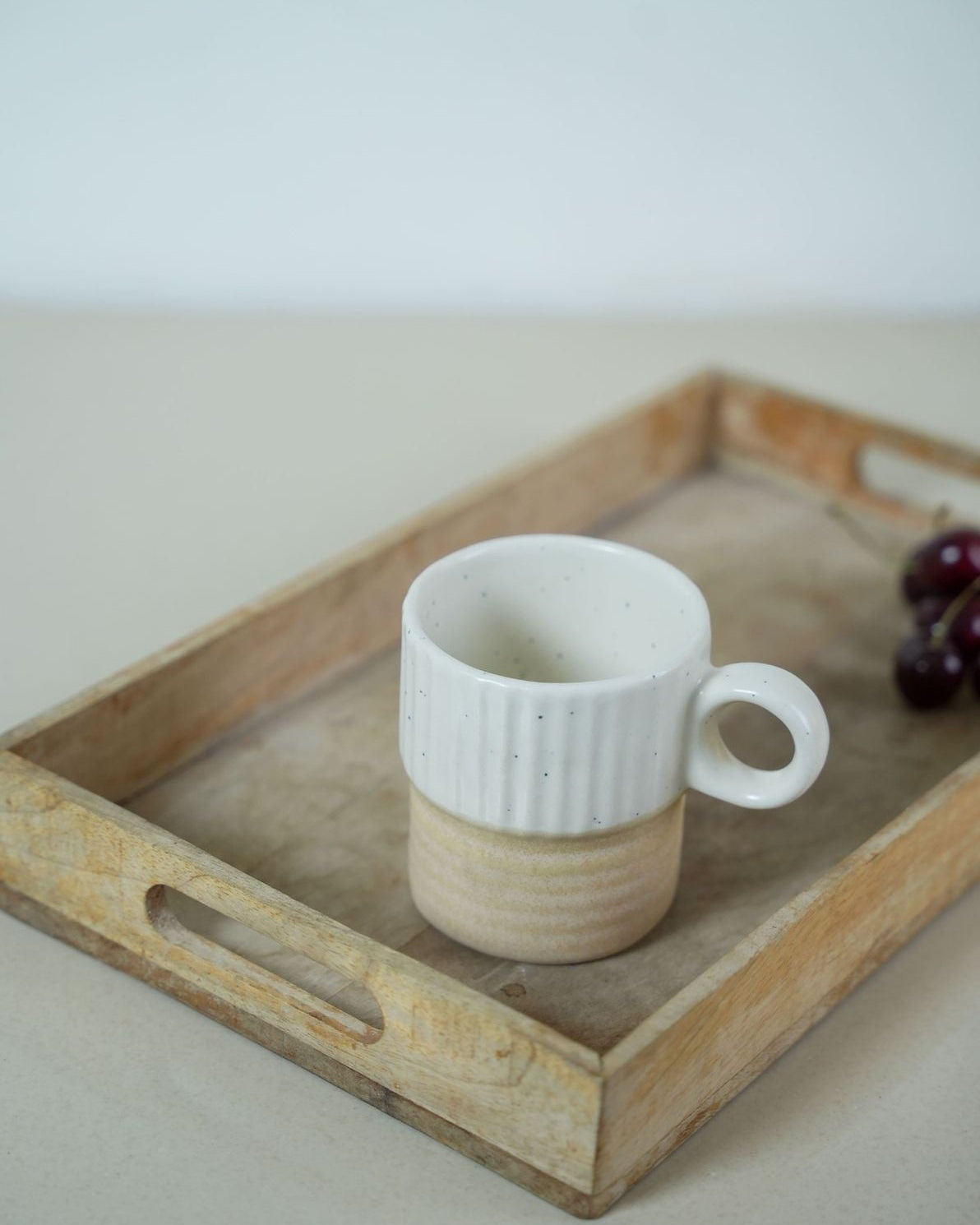 ceramic mug with ribbed texture on a wooden tray against a light background