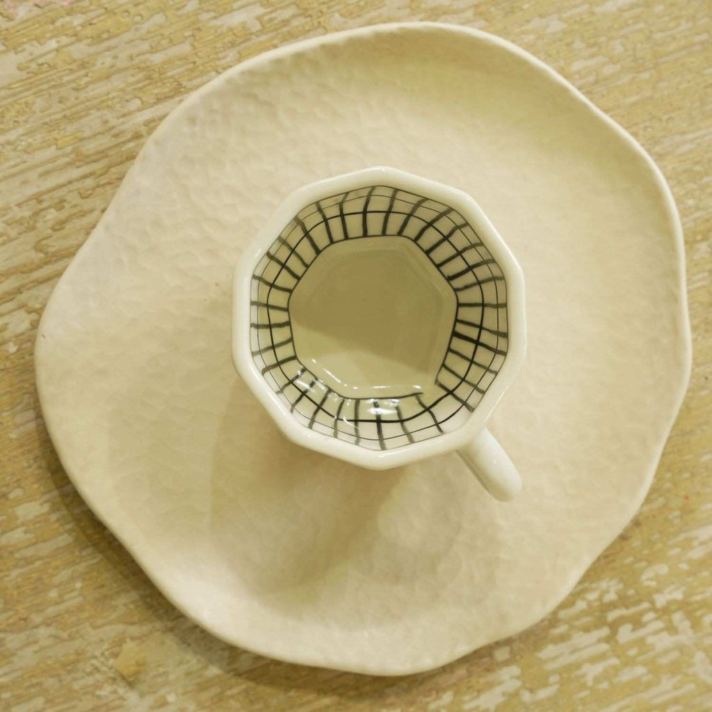 Ceramic cup with a geometric design on a matching saucer on a wooden surface