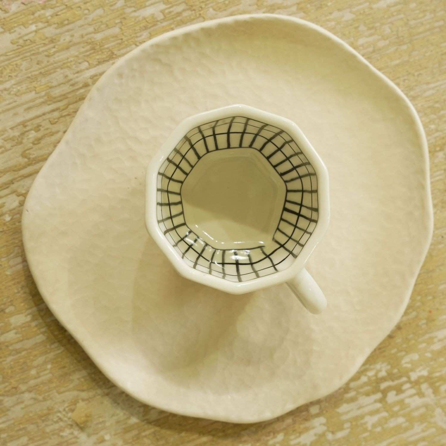 Ceramic cup with a geometric design on a matching saucer on a wooden surface