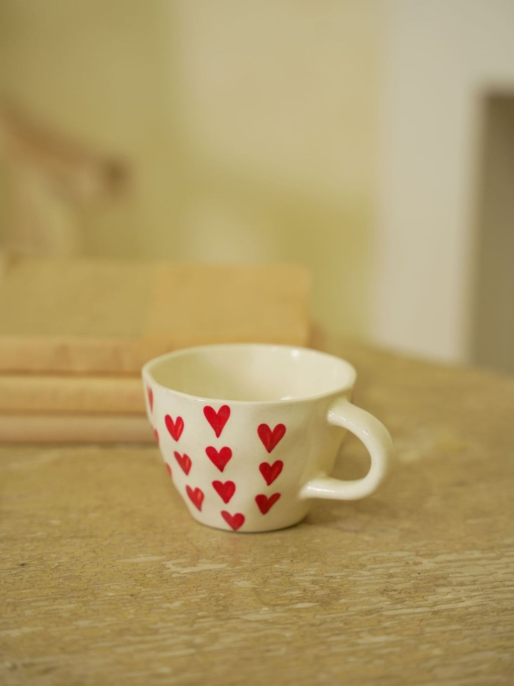 White mug with red heart patterns on a wooden surface