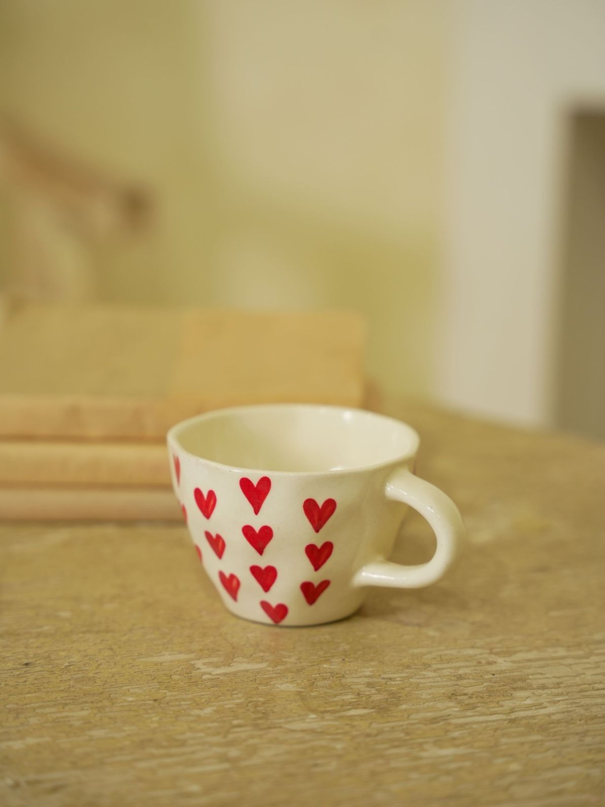 White mug with red heart patterns on a wooden surface