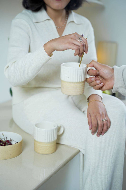 Two people sharing sumeko cup of coffee in a cozy setting.