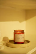 Candle labeled 'warm vanilla' on a textured surface with a warm glow